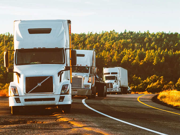 image of three white semi-trucks parked on the side of a road