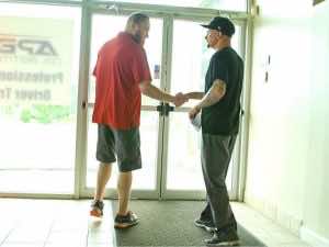 two people shaking hands in front of Apex building doors