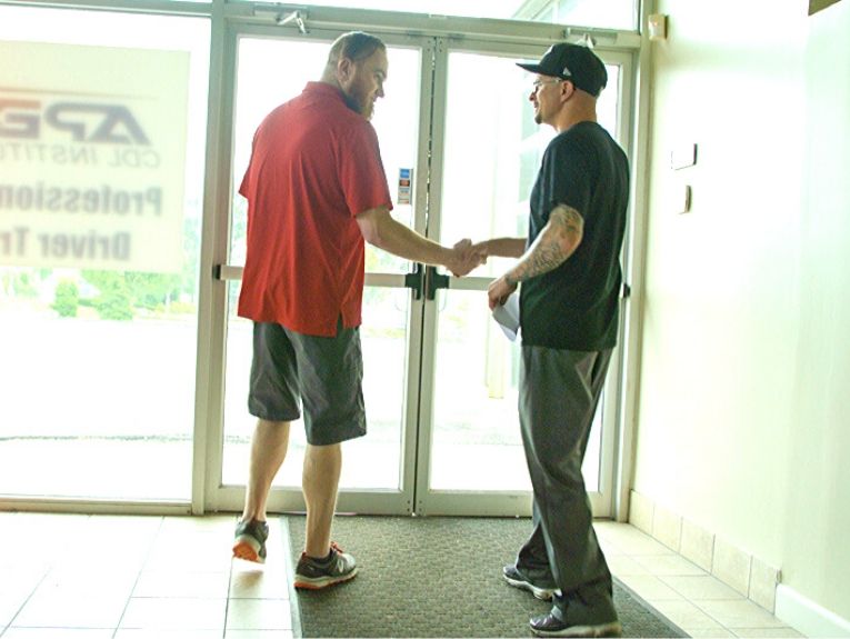 image of two people shaking hands in front of Apex building doors