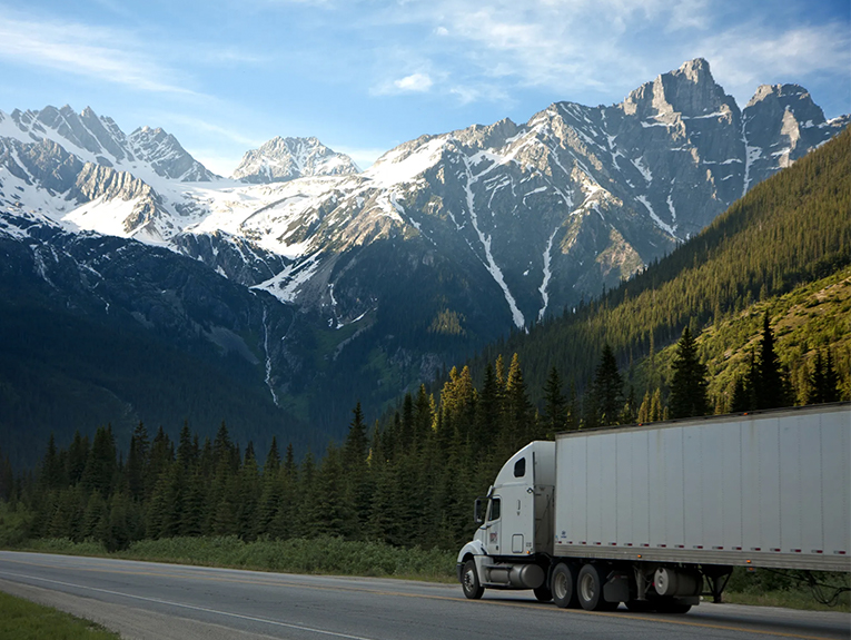 image of white semi-truck driving on mountainous highway