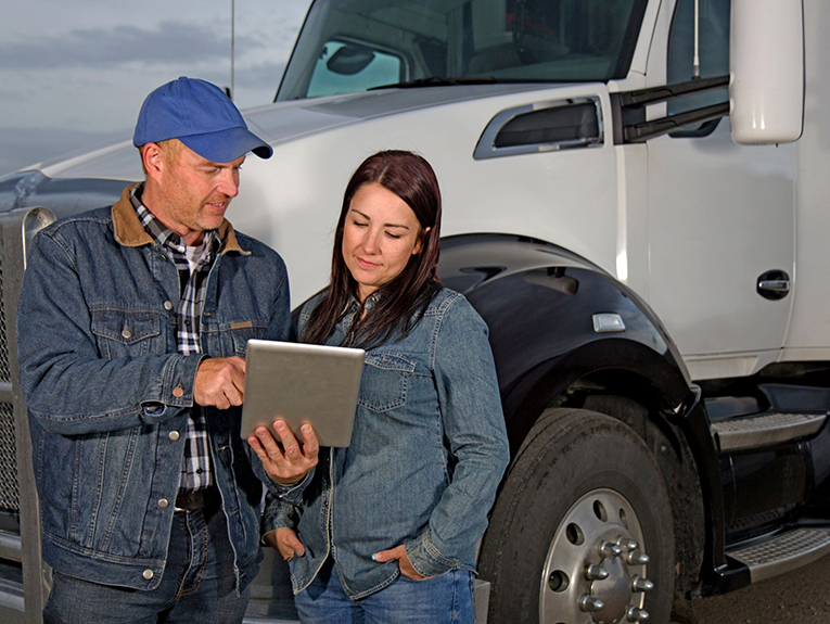 image of two drivers standing in front of white semi looking at a tablet
