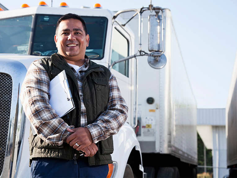 image of truck driver standing in front of white semi holding clipboard