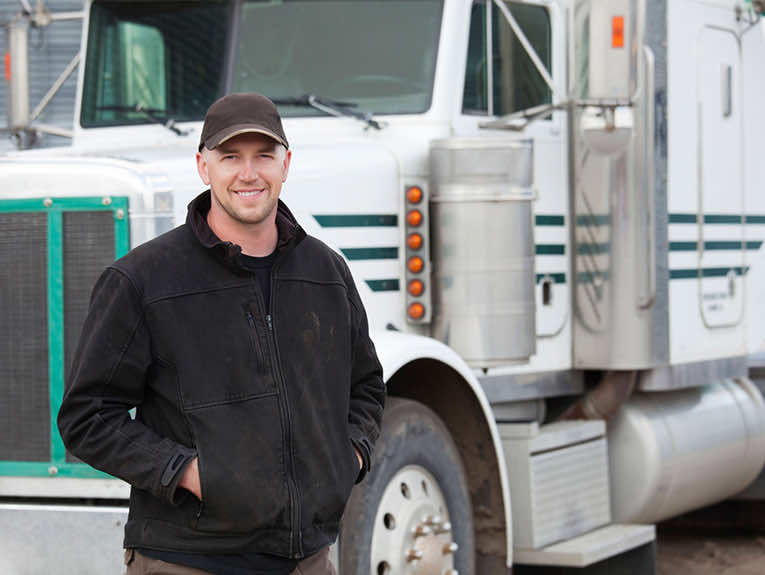 image of smiling driver standing in front of white truck