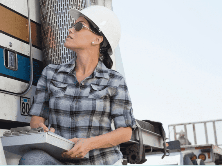 image of woman holding clipboard leaning against semi