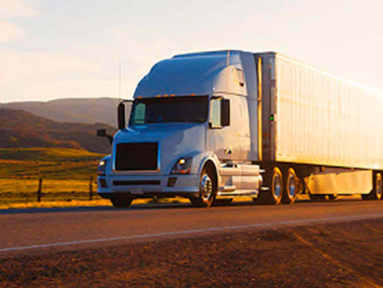 image of white semi driving away from sunset