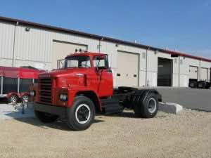 red semi truck from the 1960's parked in front of garage