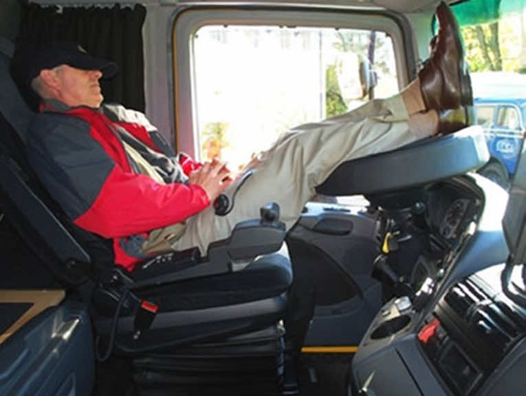 image of man in truck sleeping with feet on wheel