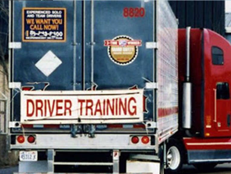 image of the back of red and white semi truck, a banner hanging on the back reads "Driver Training"