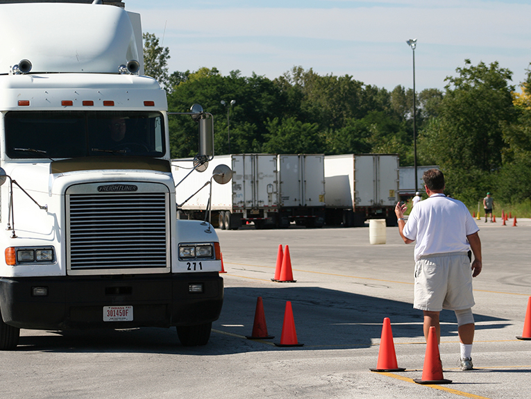 White truck on the left, with a man instructing the truck