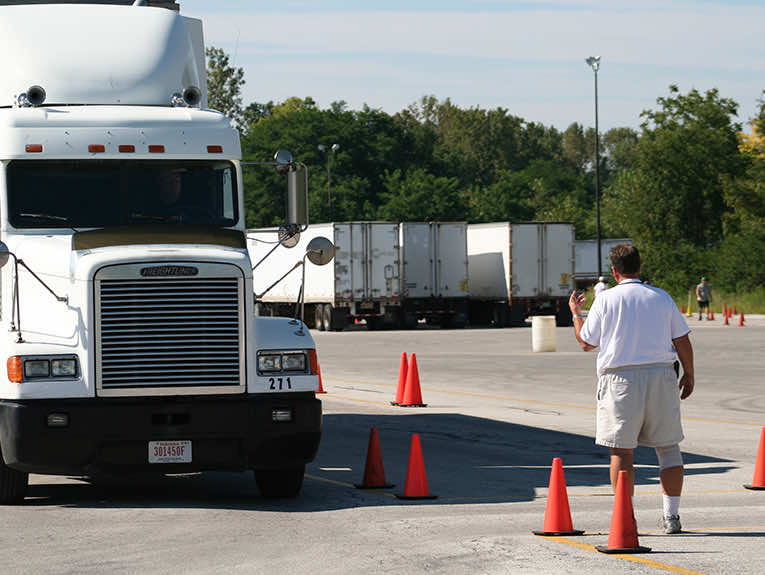 image of white truck, instructor standing outside of it