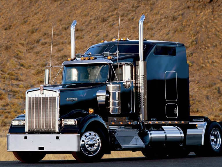 Image of black truck with smoke stacks parked in front of hill