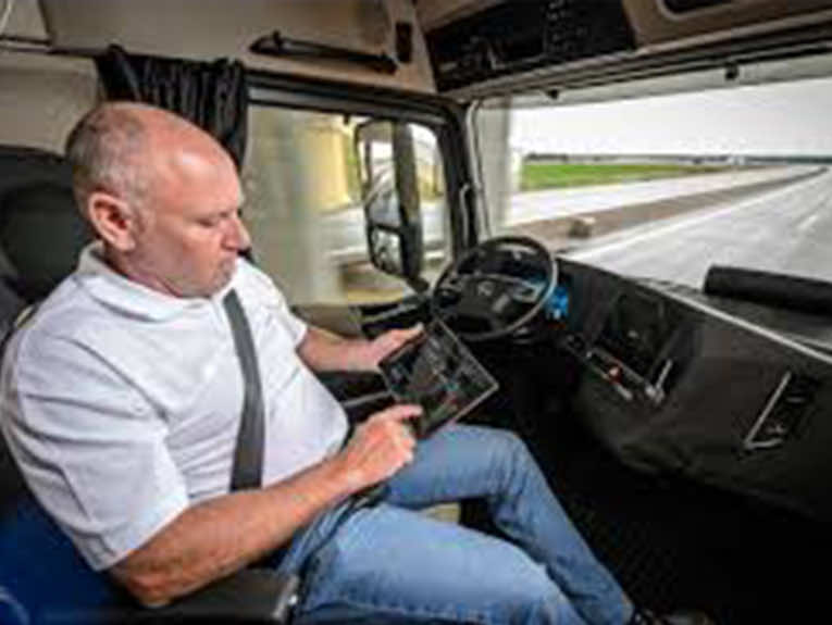 image of man sitting in drivers seat of semi truck looking at tablet