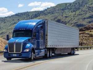 blue and white truck driving past hills