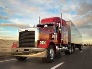 image of red and white semi driving on road, blurred to show motion