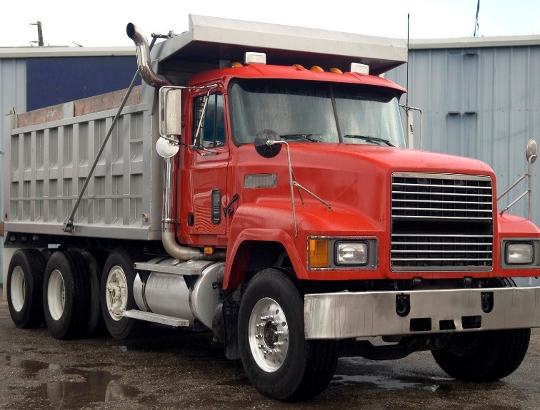 Red dump truck parked near a building
