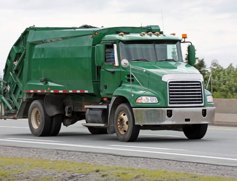 Green garbage truck on the road