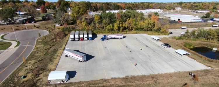 Bird's eye view of Apex Technical Insitute's CDL training yard. 7 semi trucks lined up on a large paved range just beyond the main facility.