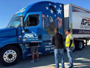 Instructor watching student climb into front seat of semi truck